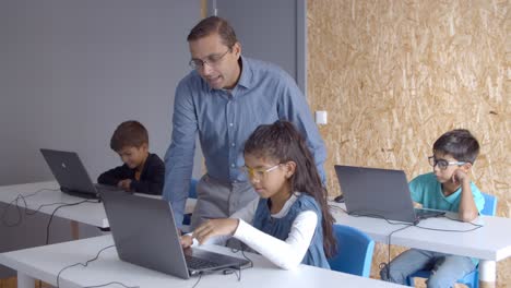 Computer-science-teacher-helping-pupil