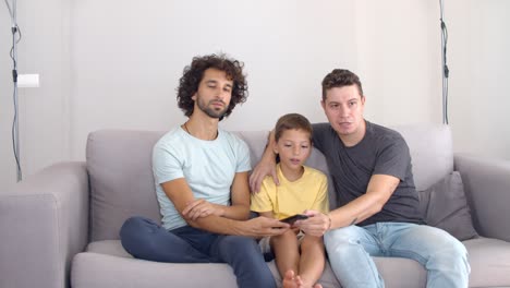 Two-focused-fathers-and-son-setting-parameters-on-new-TV