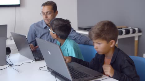 Computer-science-teacher-teaching-schoolboys-to-write-codes