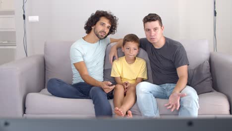 Two-fathers-and-son-watching-movie-on-TV-at-home
