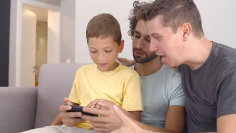Pensive-boy-sitting-on-fathers-lap-and-studying-new-app