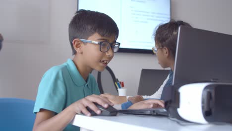 Aufgeregter-Schülerjunge-Mit-Brille-Sitzt-Am-Schreibtisch-Und-Benutzt-Laptop