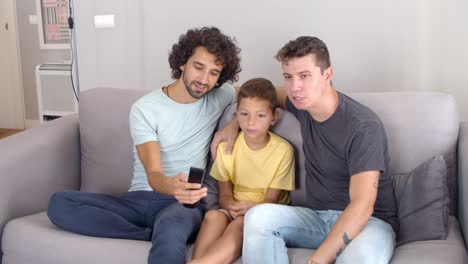 Two-focused-dads-and-son-studying-remote-control-for-new-TV