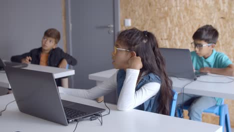 Chica-Pensativa-Con-Gafas-Sentada-En-El-Escritorio-Con-Una-Computadora-Portátil