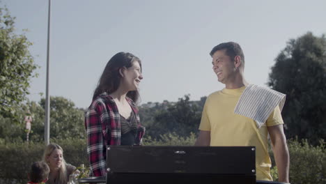 Happy-man-and-teenage-daughter-talking-at-barbecue-grill