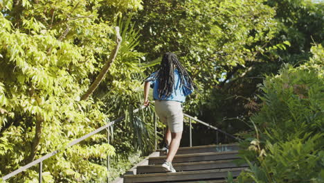 Back-view-of-African-American-woman-running-up-stairs-in-park