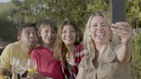 Happy-woman-taking-selfie-of-her-grimacing-family-outdoors