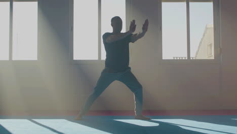 Concentrated-man-practicing-tai-chi-in--sunlight-indoor