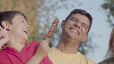 Close-up-of-happy-preteen-boy-giving-shashlik-to-his-father