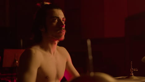 Energetic-shirtless-male-drummer-with-beard-playing-drums