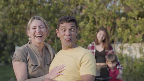 Happy-mid-adult-couple-laughing-and-grimacing-at-camera-outdoors