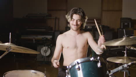 Young-shirtless-male-drummer-with-beard-playing-drums