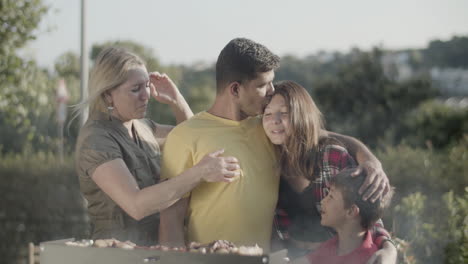 Happy-man-embracing-and-kissing-his-children-at-barbecue-grill