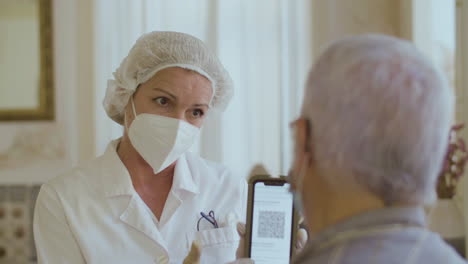 Doctor-showing-man-qr-code-on-phone-screen-after-vaccination