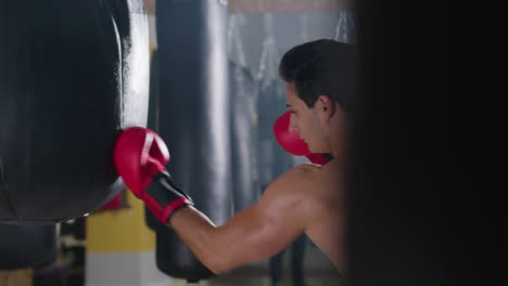 Young-male-boxer-hitting-punching-bag-in-gym