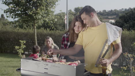 Happy-man-cooking-food-on-barbecue-grill-with-teenage-daughter