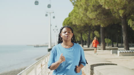 Front-view-of-tired-woman-jogging-along-running-track-in-park