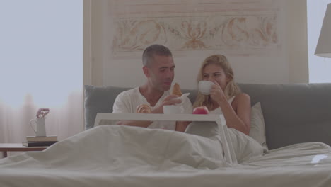 Happy-Caucasian-couple-having-breakfast-in-bed-at-home