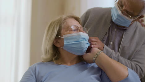 Medium-shot-of-man-helping-wife-putting-on-protective-mask