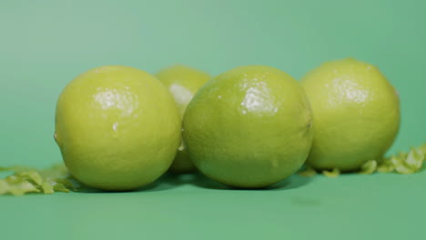 Nahaufnahme-Von-Saftigen-Frischen-Limettenfrüchten-Auf-Einer-Isolierten-Grünen-Oberfläche