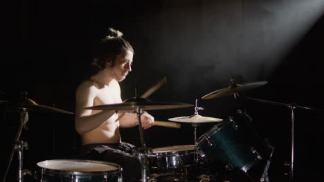 Energetic-shirtless-male-drummer-with-beard-playing-drums