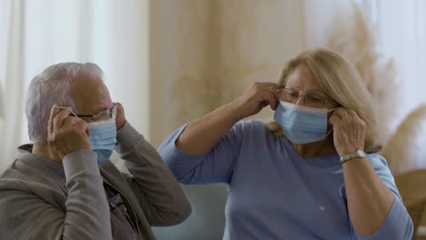 Medium-shot-of-mature-couple-putting-on-protective-masks-at-home