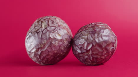 Two-whole-avocado-fruit-rotating-on-isolated-pink-surface