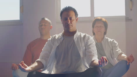 Gruppe-älterer-Menschen,-Die-Drinnen-Im-Lotussitz-Meditieren