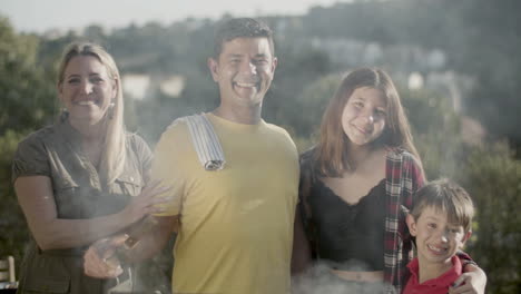 Portrait-of-happy-family-standing-at-barbecue-grill-and-smiling