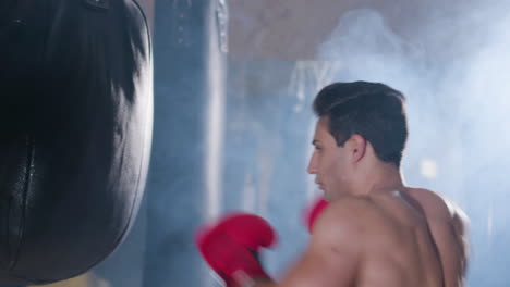 Boxeador-Masculino-Fuerte-Golpeando-El-Saco-De-Boxeo-Con-Fuerza