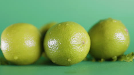 Nahaufnahme-Ganzer-Frischer-Limettenfrüchte-Auf-Einer-Isolierten-Grünen-Oberfläche