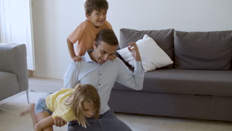 Exited-Caucasian-man-playing-with-children-and-showing-strength
