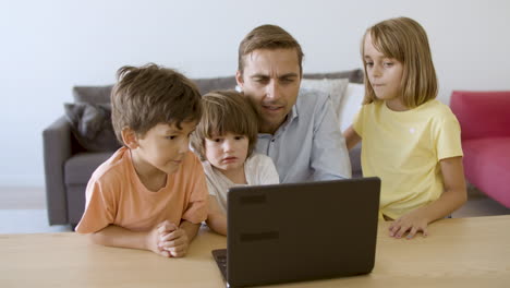 Caucasian-dad-watching-movie-via-laptop-with-kids