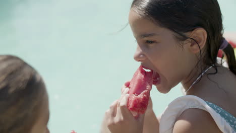 Closeup-of-girls-face-while-eating-watermelon-by-swimming-pool.