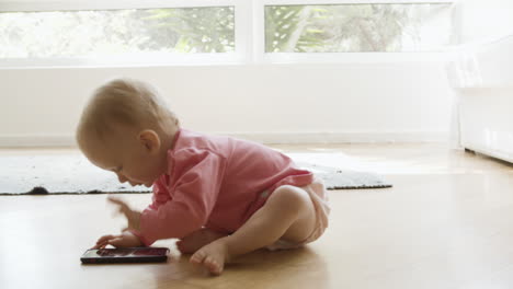Entzückendes-Kleines-Mädchen,-Das-Auf-Dem-Boden-Sitzt-Und-Mit-Dem-Smartphone-Spielt