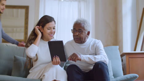 Caucasian-woman-helping-her-grandpa-with-using-tablet.