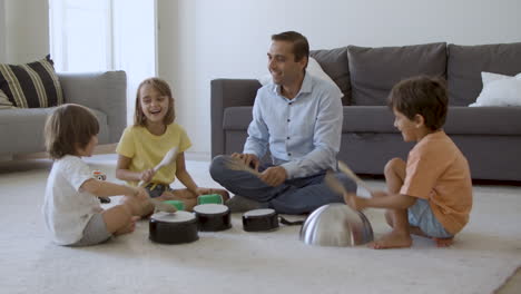 Süße-Kinder-Und-Papa-Sitzen-Auf-Dem-Teppich-Und-Spielen-Mit-Utensilien