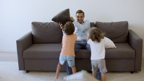 Middle-aged-dad-playing-with-kids-and-fighting-with-pillows