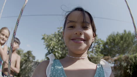 Happy-girl-taking-selfie-while-swinging-at-backyard-playground.