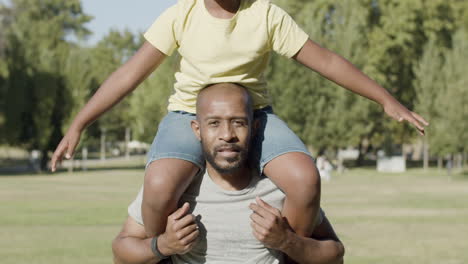 Father-carrying-his-son-on-shoulders-while-walking-in-park.