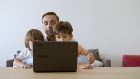 Father-showing-something-on-laptop-to-little-sons
