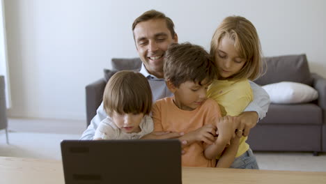 Liebender-Vater-Umarmt-Kinder-Und-Schaut-Auf-Laptop-Bildschirm