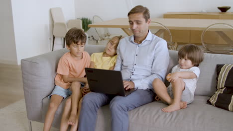 Dad-and-three-sibling-kids-relaxing-on-couch