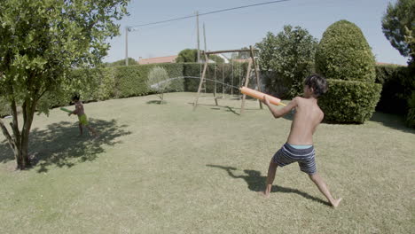 Two-boys-having-water-gun-fight-in-backyard-on-sunny-day.