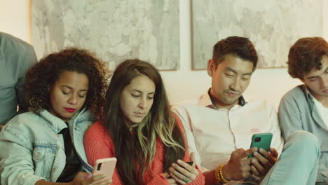 Group-of-friends-sitting-on-sofa-and-looking-at-phone-screen