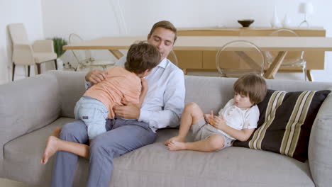 Dad-enjoying-leisure-time-with-little-sons-on-couch