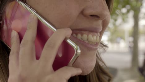 Young-woman-with-toothy-smile-talking-on-smartphone.