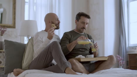 Fröhliche-Homosexuelle-Männer-Im-Pyjama,-Die-Im-Bett-Frühstücken
