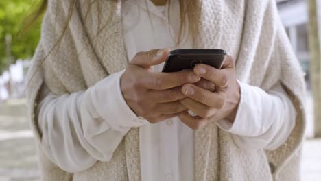 Cropped-shot-of-woman-in-white-coat-holding-smartphone.