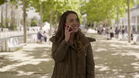 Mujer-Joven-Sonriente-Hablando-Por-Teléfono-En-El-Parque.